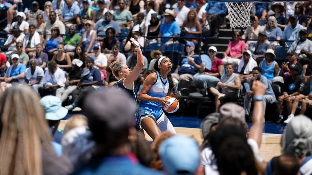 Angel Reese in action on the court amidst a cheering crowd during a WNBA game.