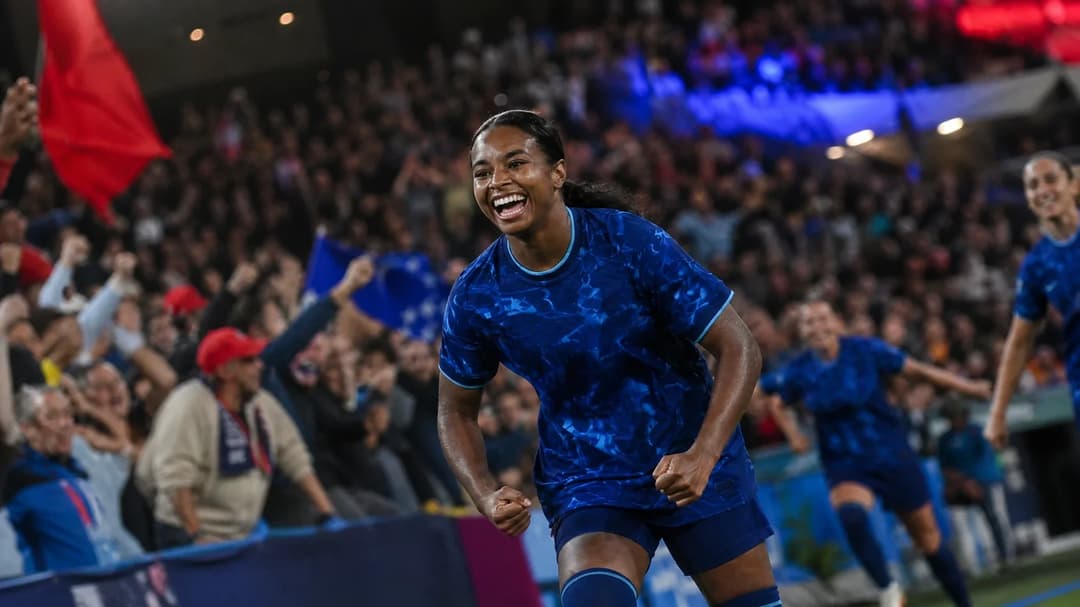 Trinity Byars celebrating a goal in front of a lively crowd in a stadium.