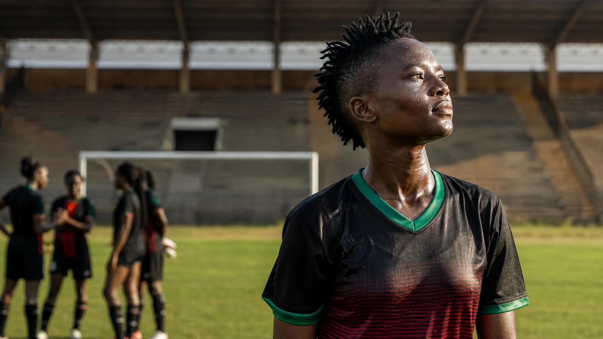 A female football player in sports attire, reflecting on the field after a match.