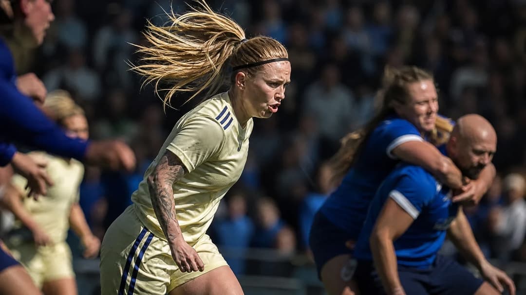 Therese Åsland in motion during a football match, surrounded by a blurred crowd.