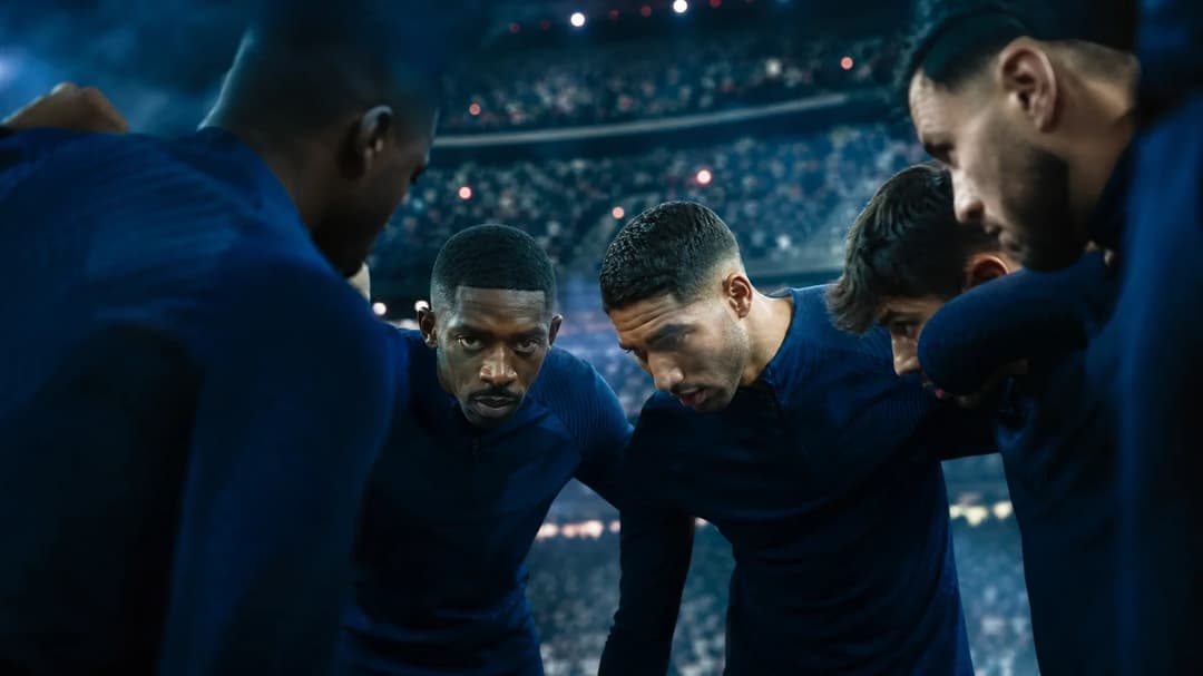 Players from Paris Saint Germain gathered in a huddle with a vibrant stadium background.
