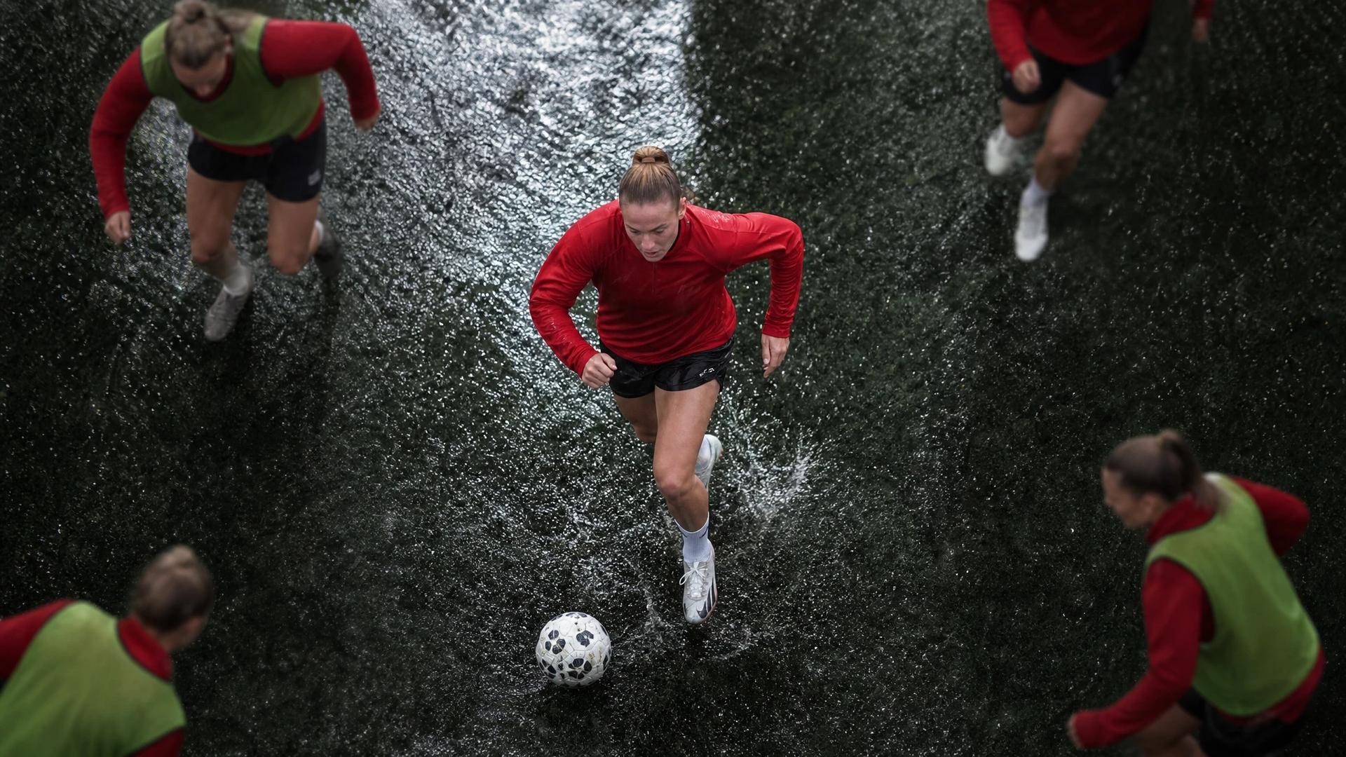 A top-down view of Jess Reavill dribbling a football during training in the rain.