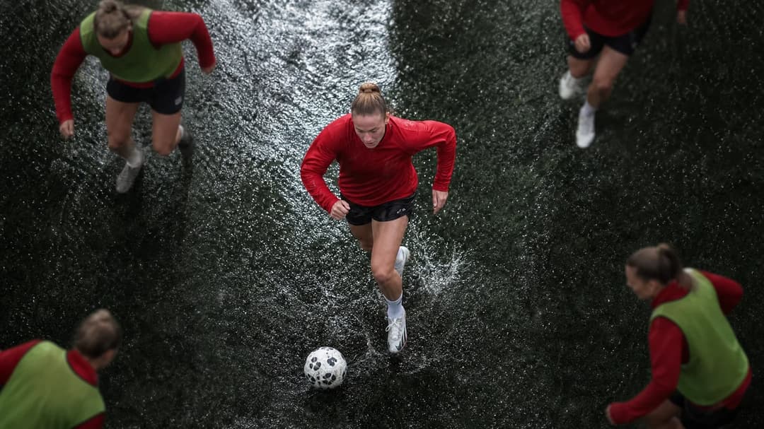 A top-down view of Jess Reavill dribbling a football during training in the rain.