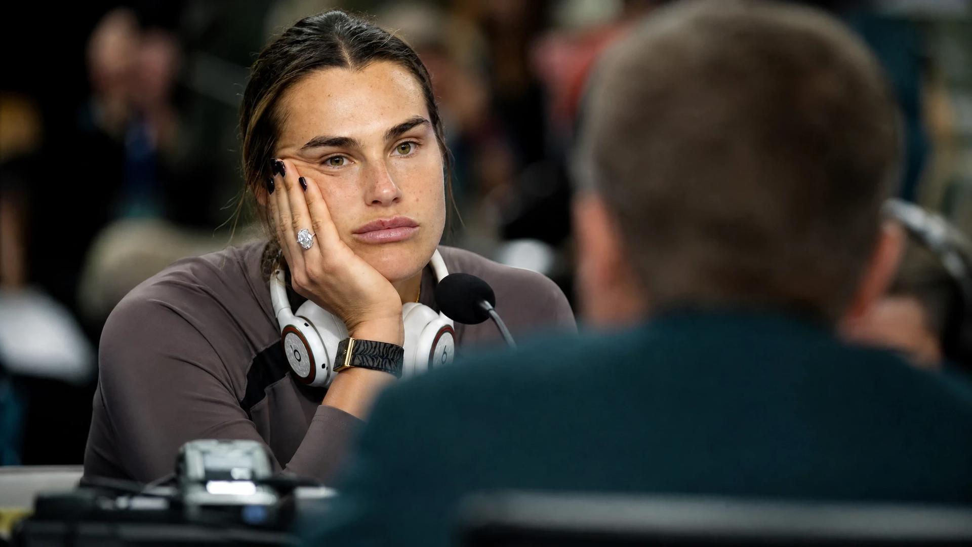 A close-up view of Aryna Sabalenka during a press conference, showing her emotional response.