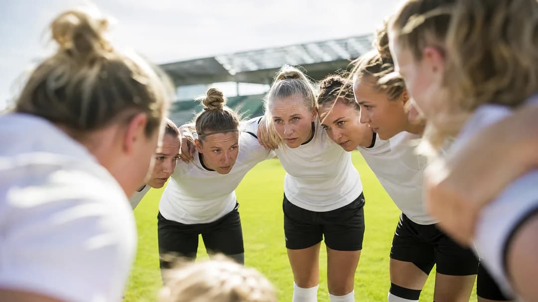 A women's football team huddled together in anticipation before a match.