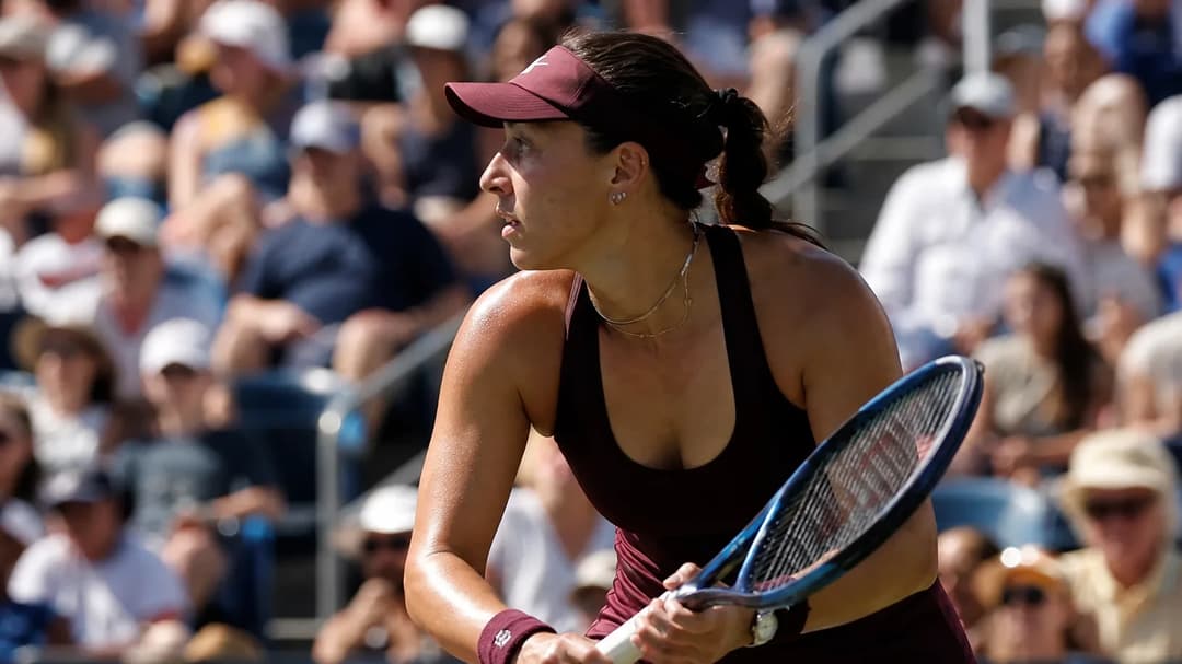 A focused Jessica Pegula playing in a tennis match at the US Open, surrounded by an excited crowd.