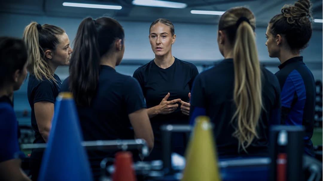 Emma Kullberg and teammates in a football training facility, engaged in a conversation.