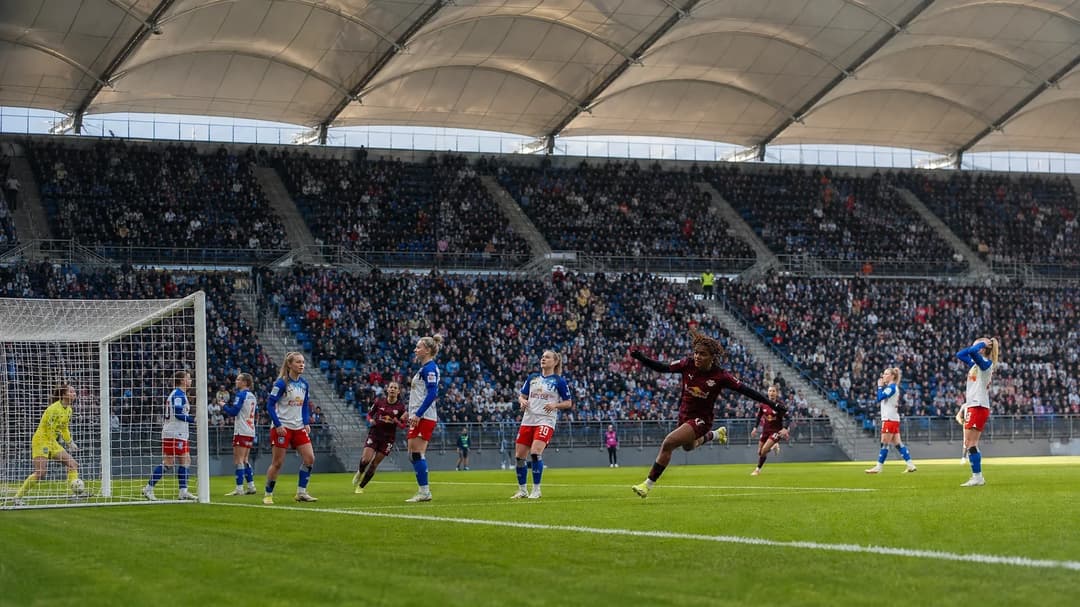 Wide shot of a women's football match at Hamburger Volksparkstadion, featuring players and cheering spectators.