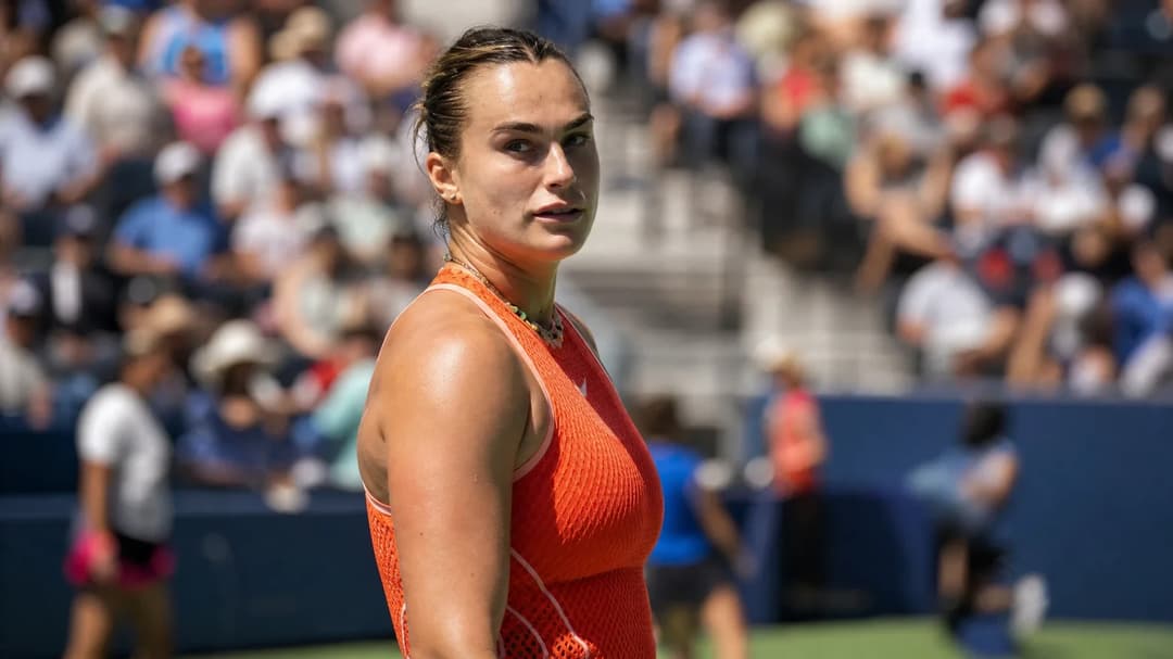 A focused Aryna Sabalenka preparing for a match with a blurred crowd in the background.