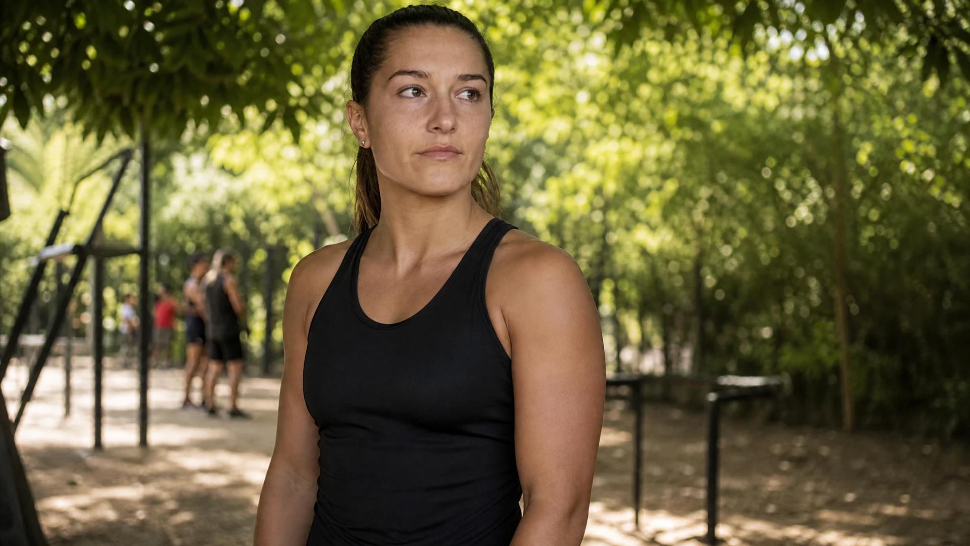 A female footballer stands in a training ground, reflecting on her new journey.