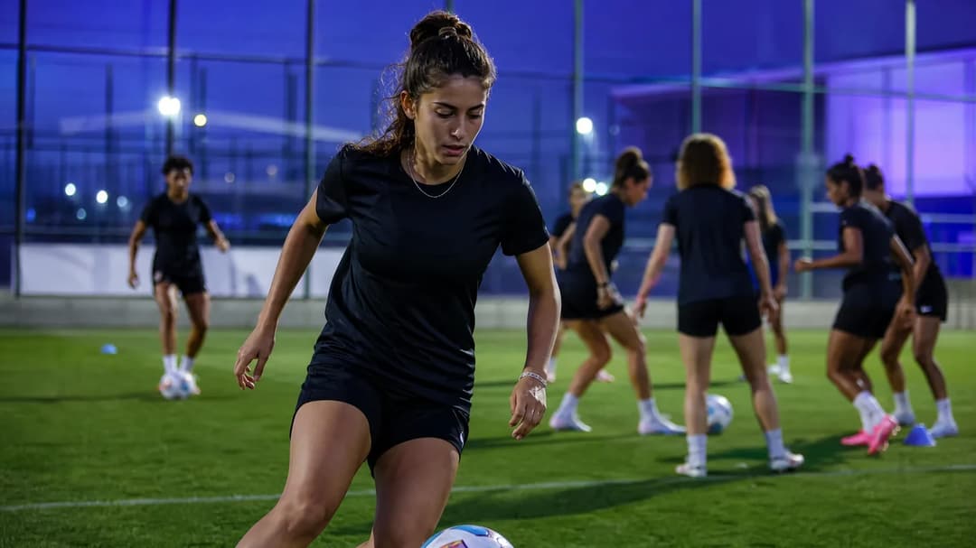Giulia Galli practicing dribbling during a training session with her teammates in a vibrant, neon-lit environment.