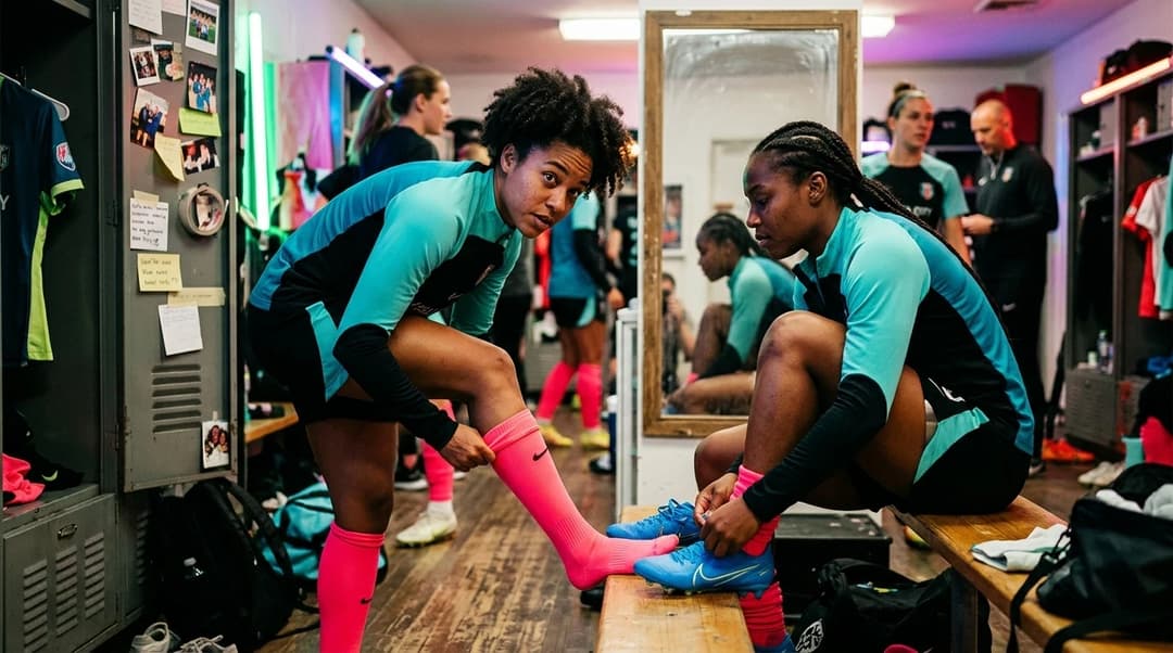 Female football players preparing in a locker room, adjusting their soccer gear.
