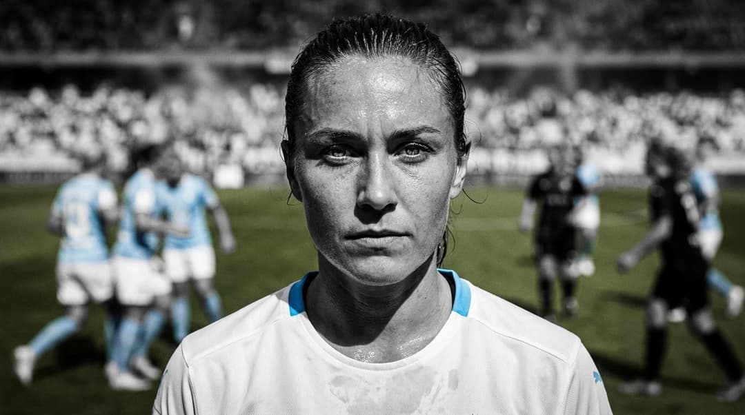 A close-up of a female football player from Malmö FF, displaying determination during a match.