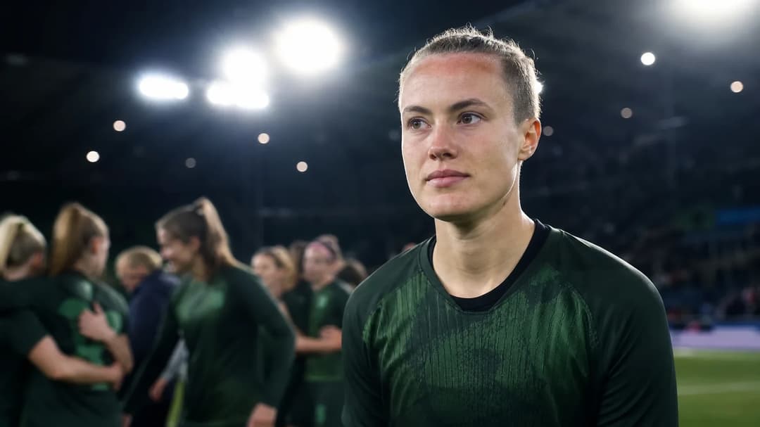 A VfL Wolfsburg female football player walks off the pitch after a match, showing determination despite disappointment.