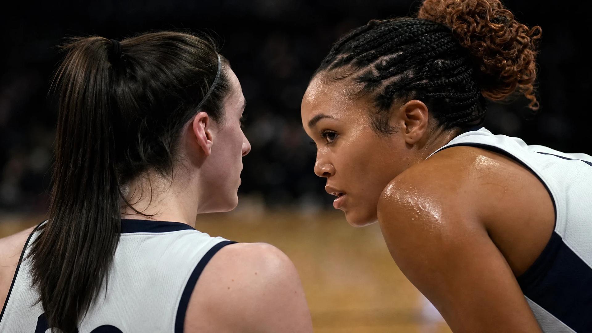 Two basketball players huddle during a timeout on the court.