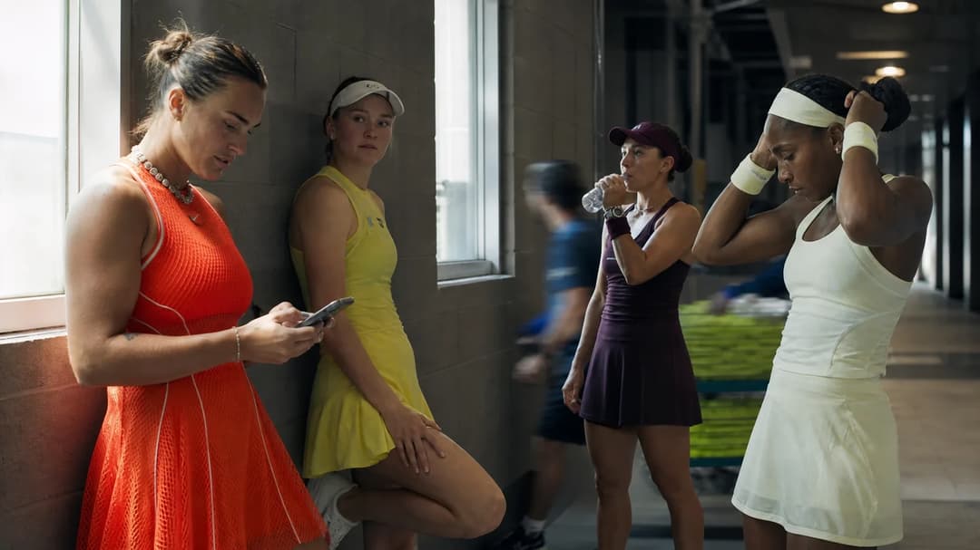 Four female tennis players discussing in a softly lit corridor at the US Open.