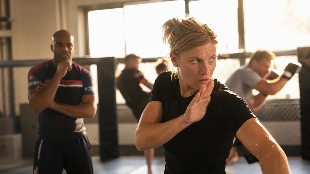 Manon Fiorot executing a karate defense move during training with her coach Flavio Santiago in the background.