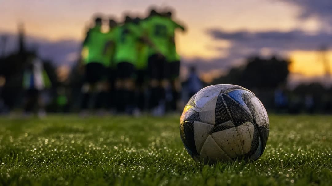 A close-up of a football on a grassy field during dusk.