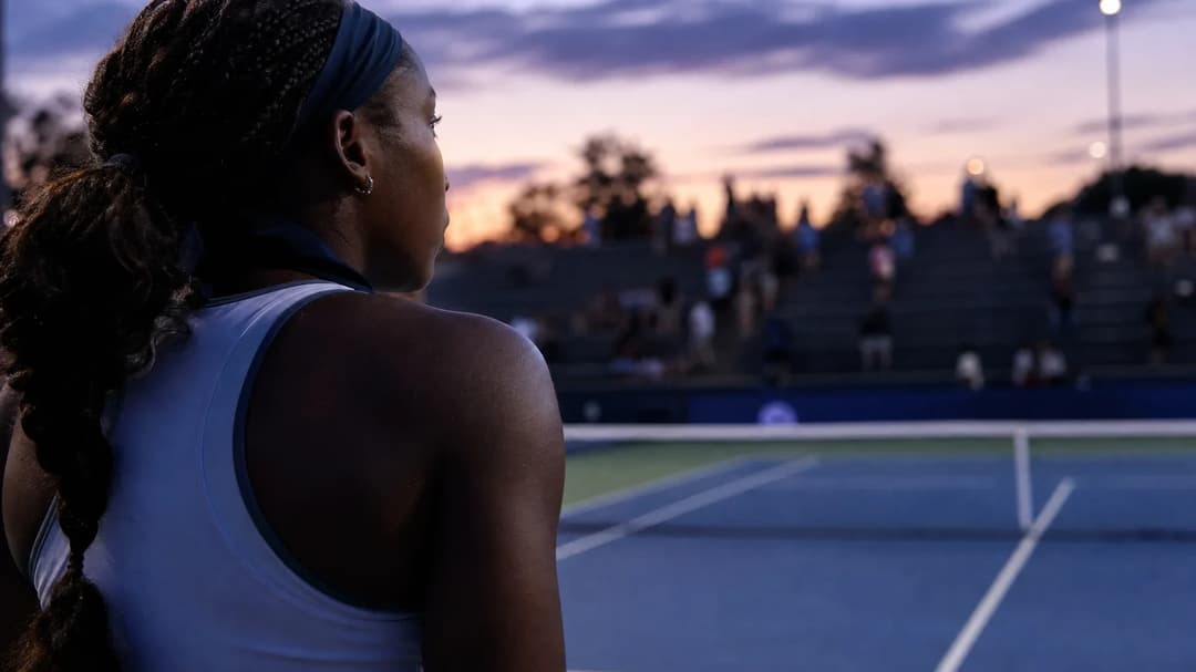 Coco Gauff standing on a tennis court at dusk, reflecting after her semi-final match.