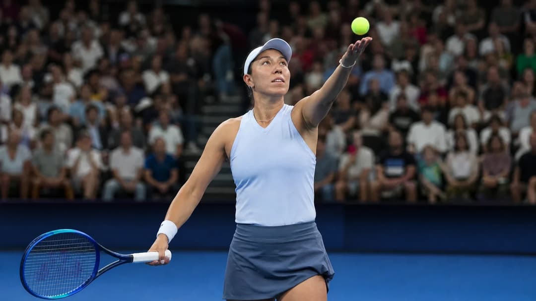 Jessica Pegula serving during a tennis match at the Singapore Open with an excited crowd in the background.